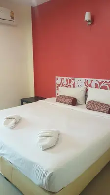 a bedroom with a large white bed with a red wall at Life&Love Resort in Ban Khlong Son