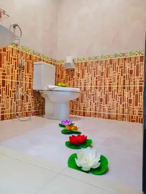 a bathroom with a toilet and flowers on the floor at Happy Holidays - 2 Minutes to Patong Beach in Patong Beach