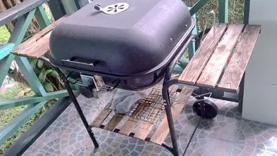 a grill sitting on a picnic table next to a bench at Swiss Chalet Garden, Pool Resort in Krabi town