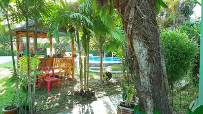 a garden with a table and chairs and palm trees at Swiss Chalet Garden, Pool Resort in Krabi town