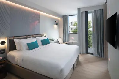 a bedroom with a large white bed and a window at JonoX Phuket Karon Hotel in Karon Beach