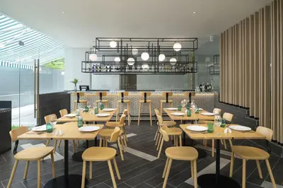 a dining room with wooden tables and chairs at JonoX Phuket Karon Hotel in Karon Beach
