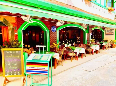 a restaurant with tables and chairs in front of a building at Grillhütte Patong in Patong Beach