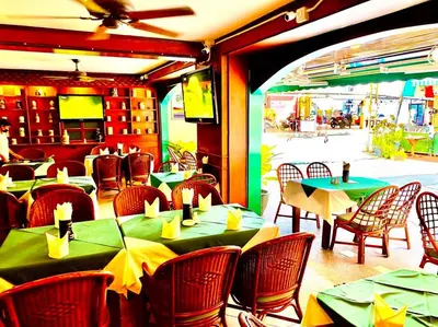 a restaurant with tables and chairs with green tables at Grillhütte Patong in Patong Beach