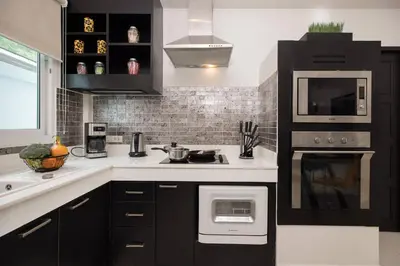 a black and white kitchen with a stove and microwave at 3BR Villa Marine with Private Pool, Waterfalls in NaiHarn Beach in Rawai Beach