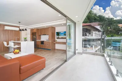 an open living room with a couch and a kitchen at seaview villa private swimming pool in Karon Beach