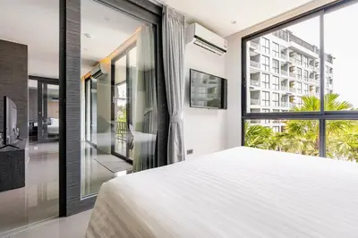 a bedroom with a large white bed and a large window at CityGate by Villacarte in Kamala Beach