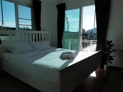 a bed in a bedroom with a large window at Charlie's Angels Hotel Restaurant in Rawai Beach