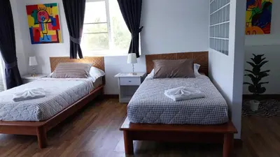 a bedroom with two beds and a window at Charlie's Angels Hotel Restaurant in Rawai Beach