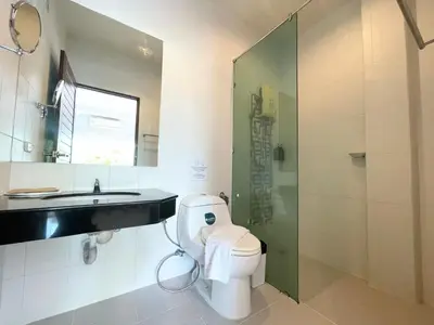 a bathroom with a toilet and a sink and a shower at The Langstan Suites in Nai Harn Beach