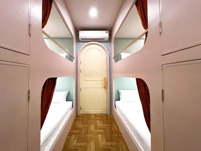 a corridor with two beds in a room at The Snug Airportel - Phuket Airport in Nai Yang Beach