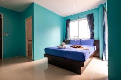 a blue bedroom with a bed with a window at PATONG BLUE HOTEL in Patong Beach