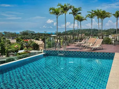 a swimming pool on top of a building with palm trees at KATA BEACH OZONE Superb Fully Equipped studio kitchen washing machine aircon in Kata Beach