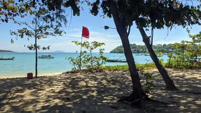 a red flag on a beach next to the water at KATA BEACH OZONE Superb Fully Equipped studio kitchen washing machine aircon in Kata Beach