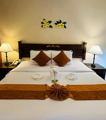 a bedroom with a large white bed with flowers on the wall at Phuket Leelavadee Hua Ting Resort in Patong Beach