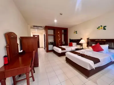 a hotel room with two beds and a desk at Phuket Leelavadee Hua Ting Resort in Patong Beach