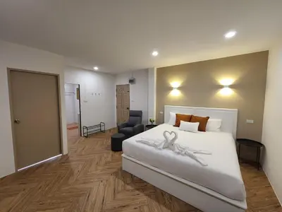 a bedroom with a large white bed and a chair at Hommory Residence - West Chalong in Ban Klang