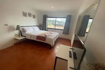 a bedroom with a bed and a large window at Swiss Villas Panoramic - Hillside Beach View in Patong Beach