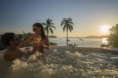 a man and a woman sitting in a bath tub with a wine glass at Villa Nirvana - Beachfront Tropical Chic 4BR Haven in Cape Panwa, Phuket in Ban Ao Makham