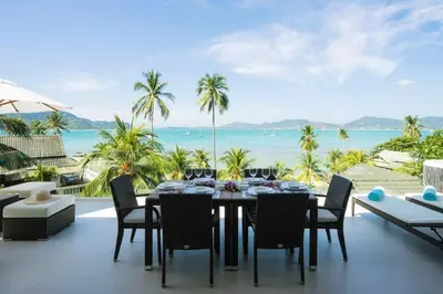 a dining table on a balcony with a view of the ocean at Villa Nirvana - Beachfront Tropical Chic 4BR Haven in Cape Panwa, Phuket in Ban Ao Makham