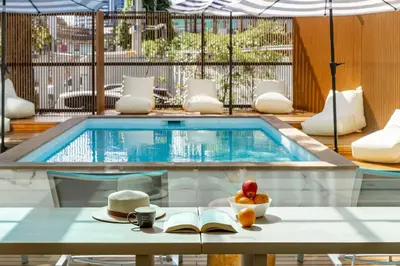 a pool with a table with a bowl of fruit and a book at The Tint At Phuket Town - SHA Plus in Phuket Town