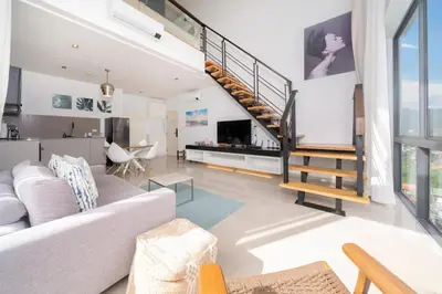 a living room with a couch and a staircase at Deluxe apartment at Icon Park by Lofty in Kamala Beach