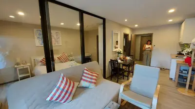 a living room with a white couch and a woman in a kitchen at Cozy Apartment Close to Amazing Beach ! 39 Sqm in Phuket Town