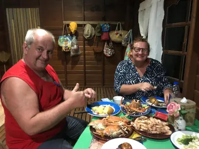 a man and woman sitting at a table with food at Artist Homestay in Ko Yao Noi