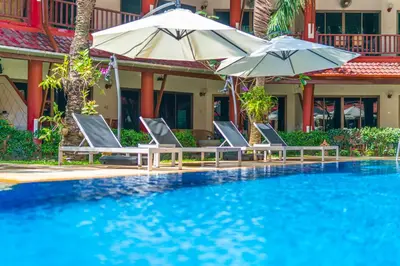 a swimming pool with two chairs and umbrellas at Sai Rougn apartment in Patong Beach