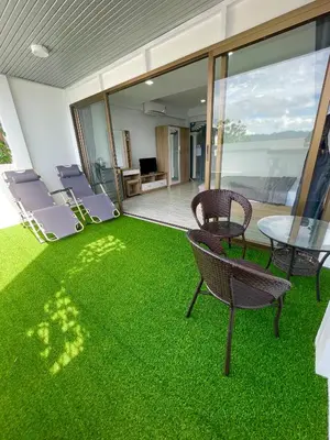 a patio with chairs and a table and grass at Apartment Sea View Patong Beach in Patong Beach