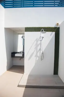 a bathroom with a shower in a white wall at The Blue Pearl Kata Hotel in Kata Beach