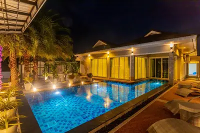 a swimming pool in front of a house at night at 3 Bedroom Platinum Pool Villa Smooth as Silk in Ban Khlong Haeng