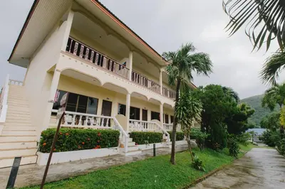a building with a balcony and palm trees at Kataonsea bungalows in Kata Beach