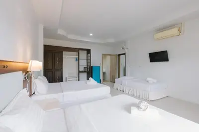 a white room with two beds and a tv at Kataonsea bungalows in Kata Beach