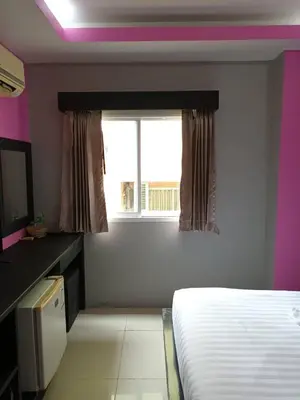 a bedroom with a white bed and a window at Lavender Patong Hotel in Patong Beach