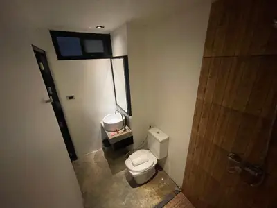 a small bathroom with a toilet and a window at Cokoon Islanda Patong Hotel in Patong Beach