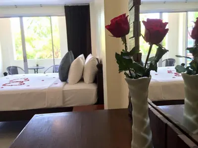 a hotel room with two beds and a table with roses at Glitter House in Phuket Town