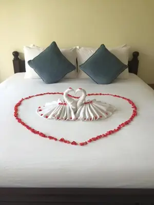 two swans are forming a heart on a bed at Glitter House in Phuket Town