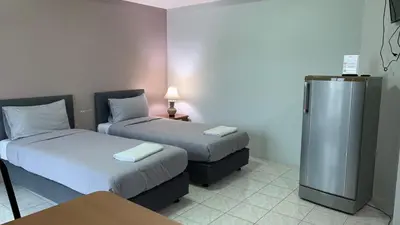 a hotel room with two beds and a refrigerator at Kamalaburi Guesthouse in Kamala Beach