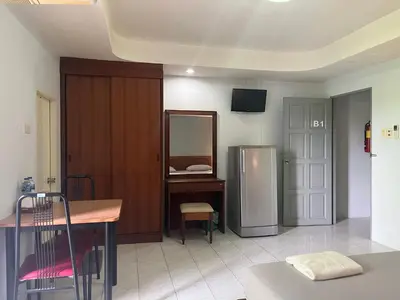 a kitchen with a refrigerator and a table and a chair at Kamalaburi Guesthouse in Kamala Beach