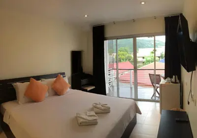 a bedroom with a large bed with a balcony at Glitter House Phuket in Kata Beach