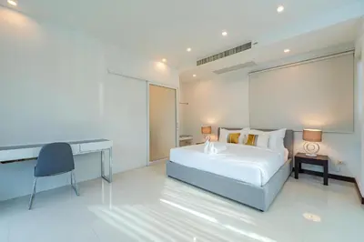 a bedroom with a bed and a desk in it at White Villa Patong in Patong Beach