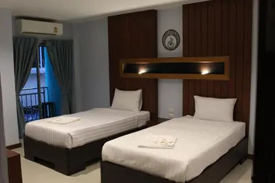 two beds in a hotel room with white sheets at Cokoon Deva Patong Hotel in Patong Beach