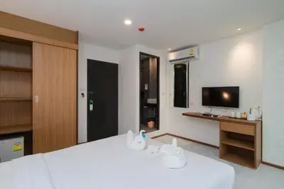 a bedroom with a large white bed and a television at Destination Patong in Patong Beach