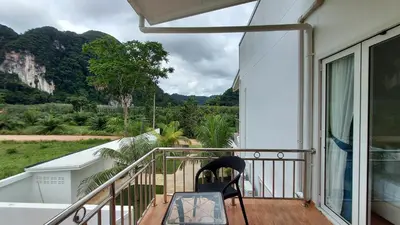 a chair on a balcony with a view of a mountain at 8 Palm Villa - Large Private Pool Villas in Aonang in Ao Nang Beach