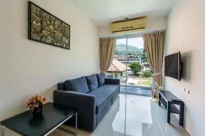 a living room with a blue couch and a tv at Chic Condominium by Redfox Hospitality in Karon Beach