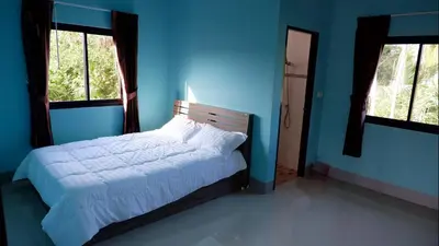 a bedroom with a bed with blue walls and windows at WS HOUSE KRABI in Ban Ko Kwang
