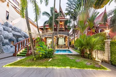 an exterior view of a house with a swimming pool and palm trees at Villa Cologne​ @Nanai Villa in Patong Beach