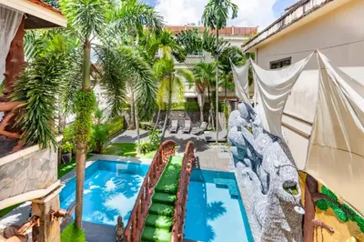 an exterior view of a resort pool with palm trees at Villa Cologne​ @Nanai Villa in Patong Beach