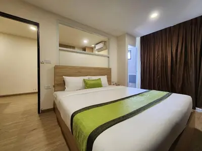a bedroom with a large bed with a green pillow at iCheck inn Darisa Patong in Patong Beach